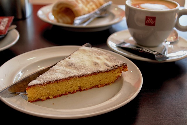 A slice of tart on a plate with a coffee cup in the background