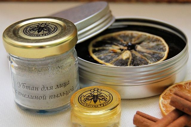 Honey and pollen face mask products in jars with some dried fruit and cinnamon sticks.