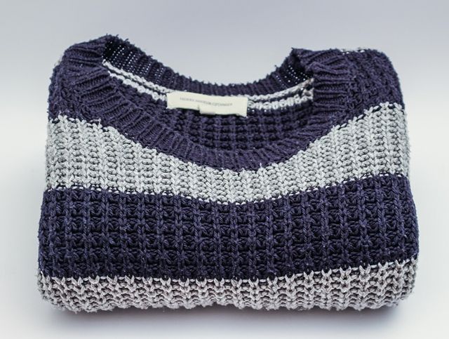 A folded knitted sweater made up of dark blue and light blue horizontal stripes.