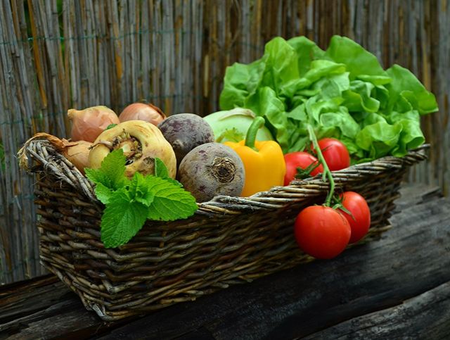 A mix of vegetables in a large wicker basket